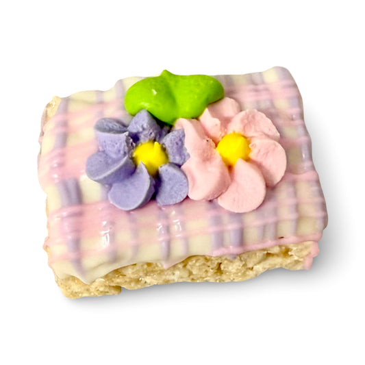 Mini Rice TreatsDipped in White Chocolate with Pink and Lavender Drizzle Decorated with Pastel Royal Icing Flowers in Cello Bag with Silver Twist Tie